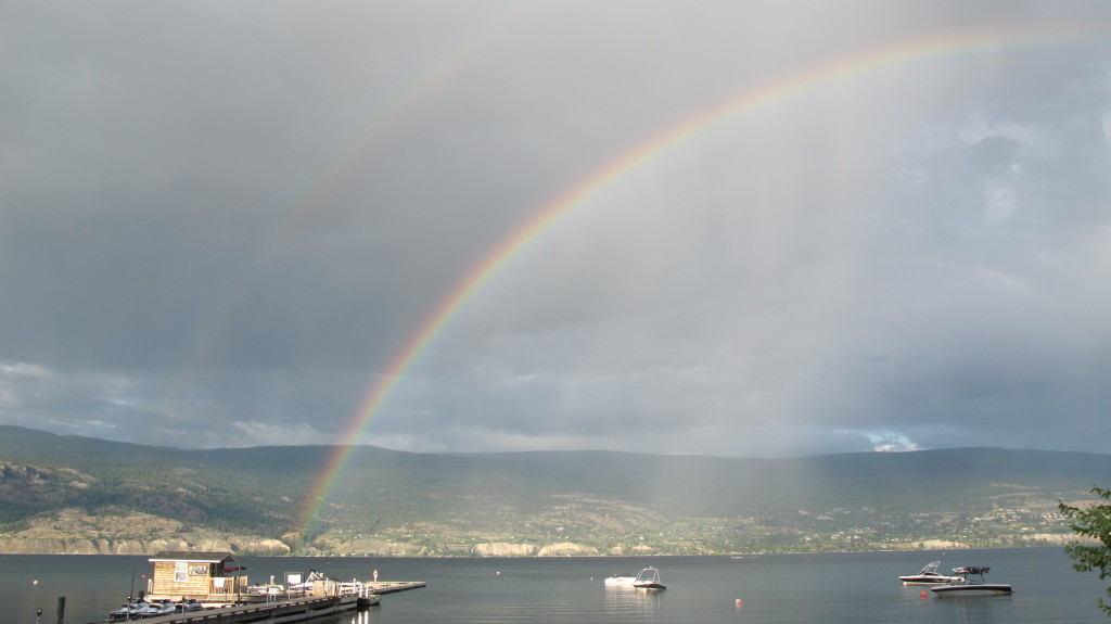 A double rainbow reaches across a quiet harbour.