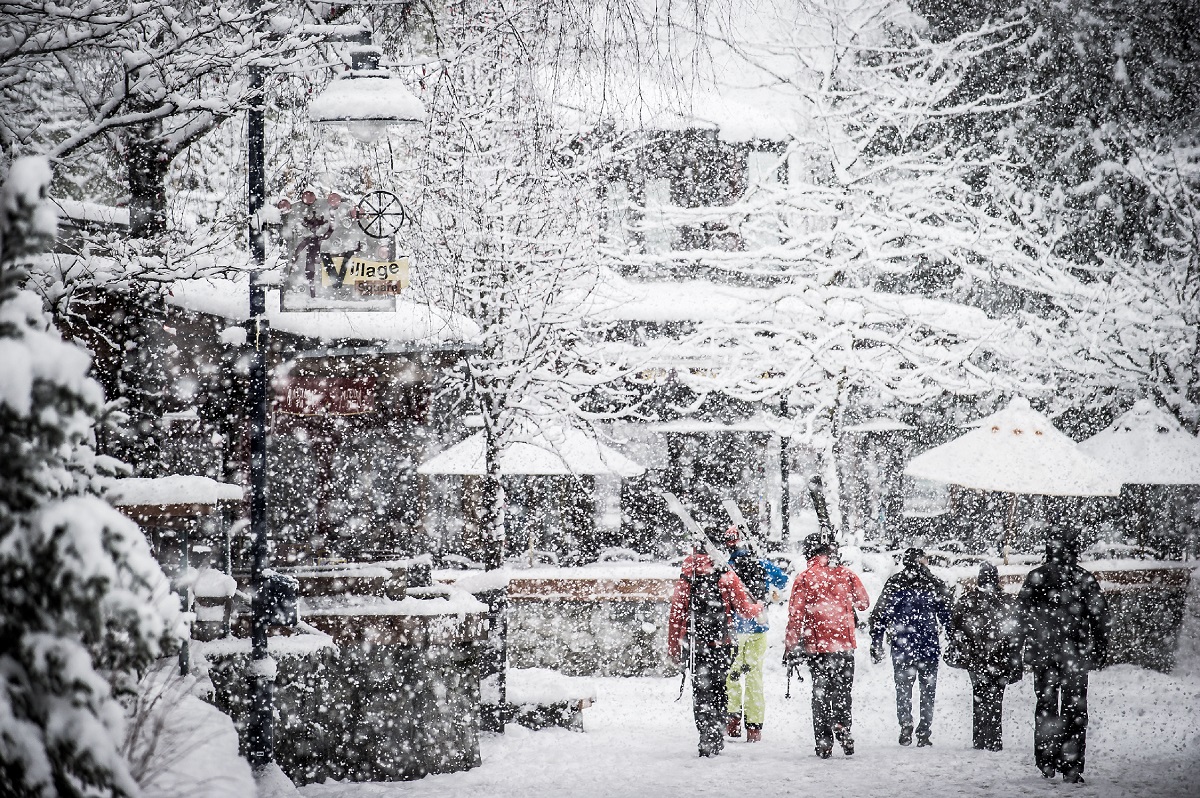 Skiers walk down a snowy street in Whistler.