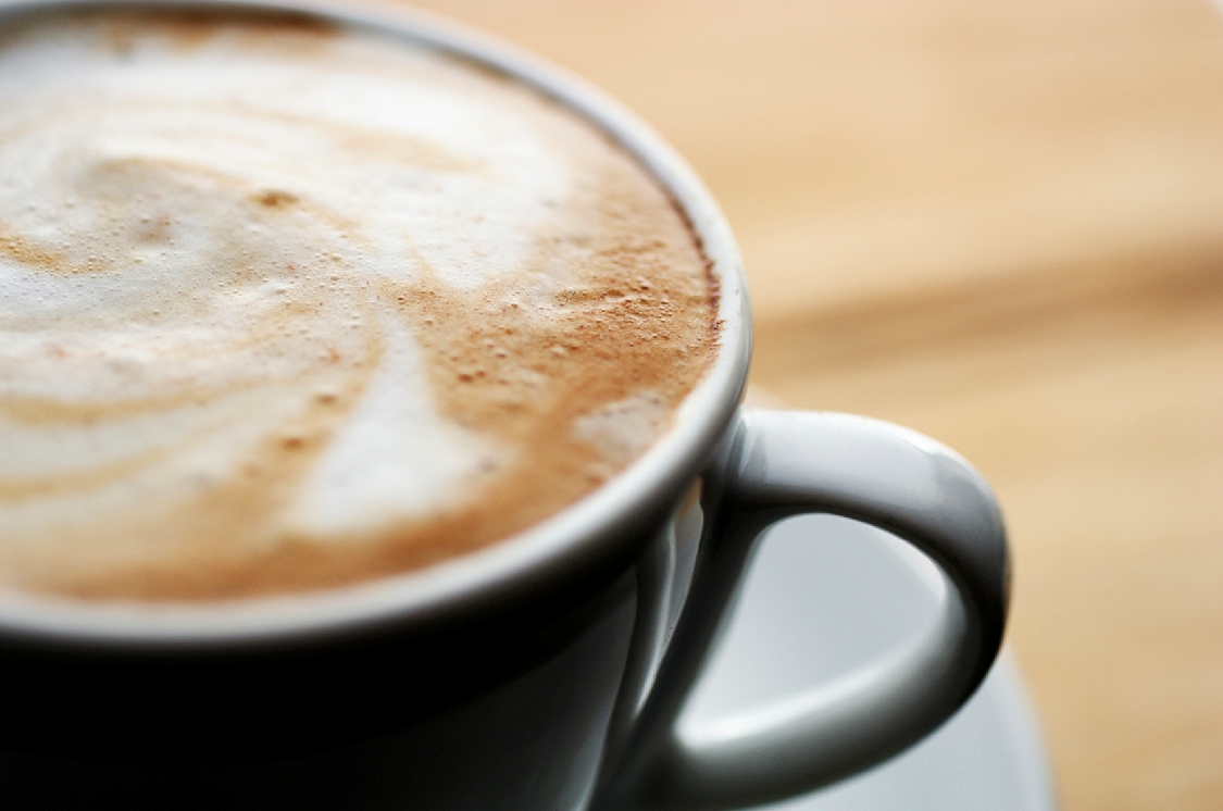 Close-up image of a cup of coffee with swirly milk froth on top.