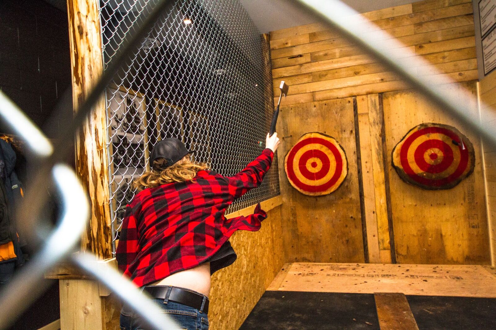 A person in red plaid shirt throws an axe at a bullseye in Revelstoke.