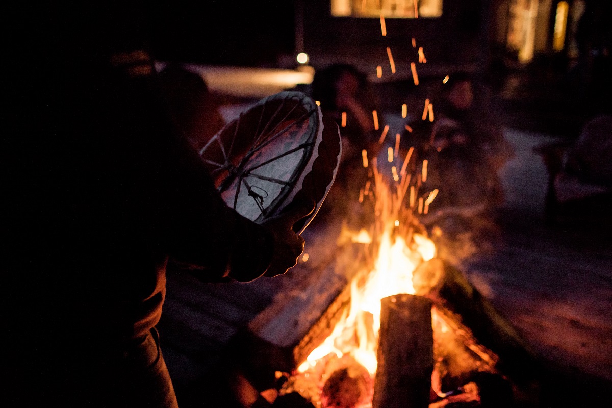 A close up on an Indigenous drum next to a wood fire at night time