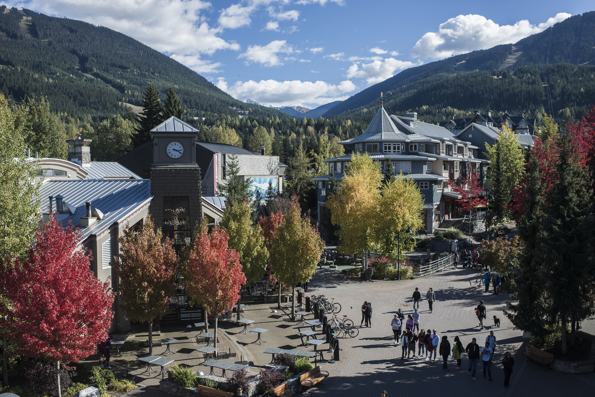 Aerial shot of Whistler Village in the fall with the clock tower in then centre and pedestrians walking through the plaza below