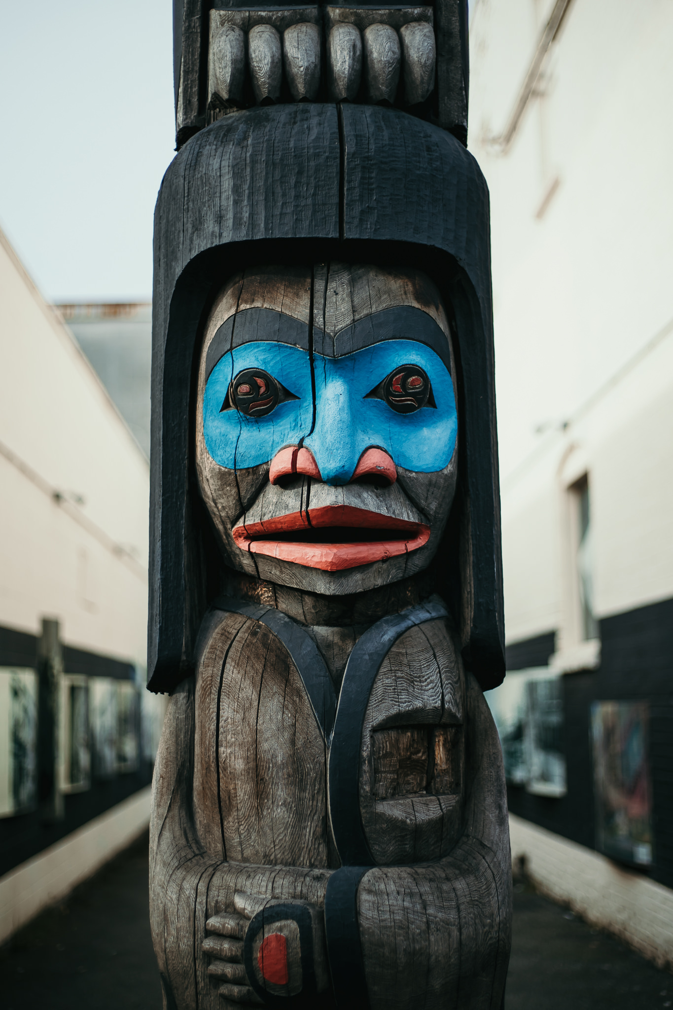 A close up of a totem pole with a blue painted eye mask and red lips and nostrils