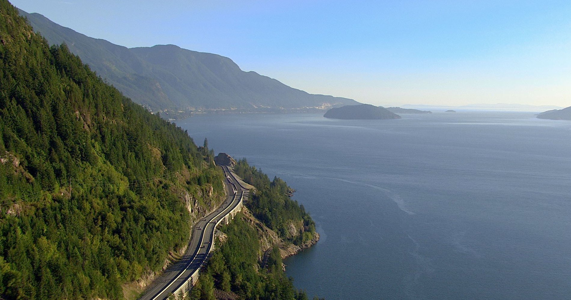 Cars driving the Sea to Sky Highway between Vancouver and Whistler with ocean and mountains in the background.