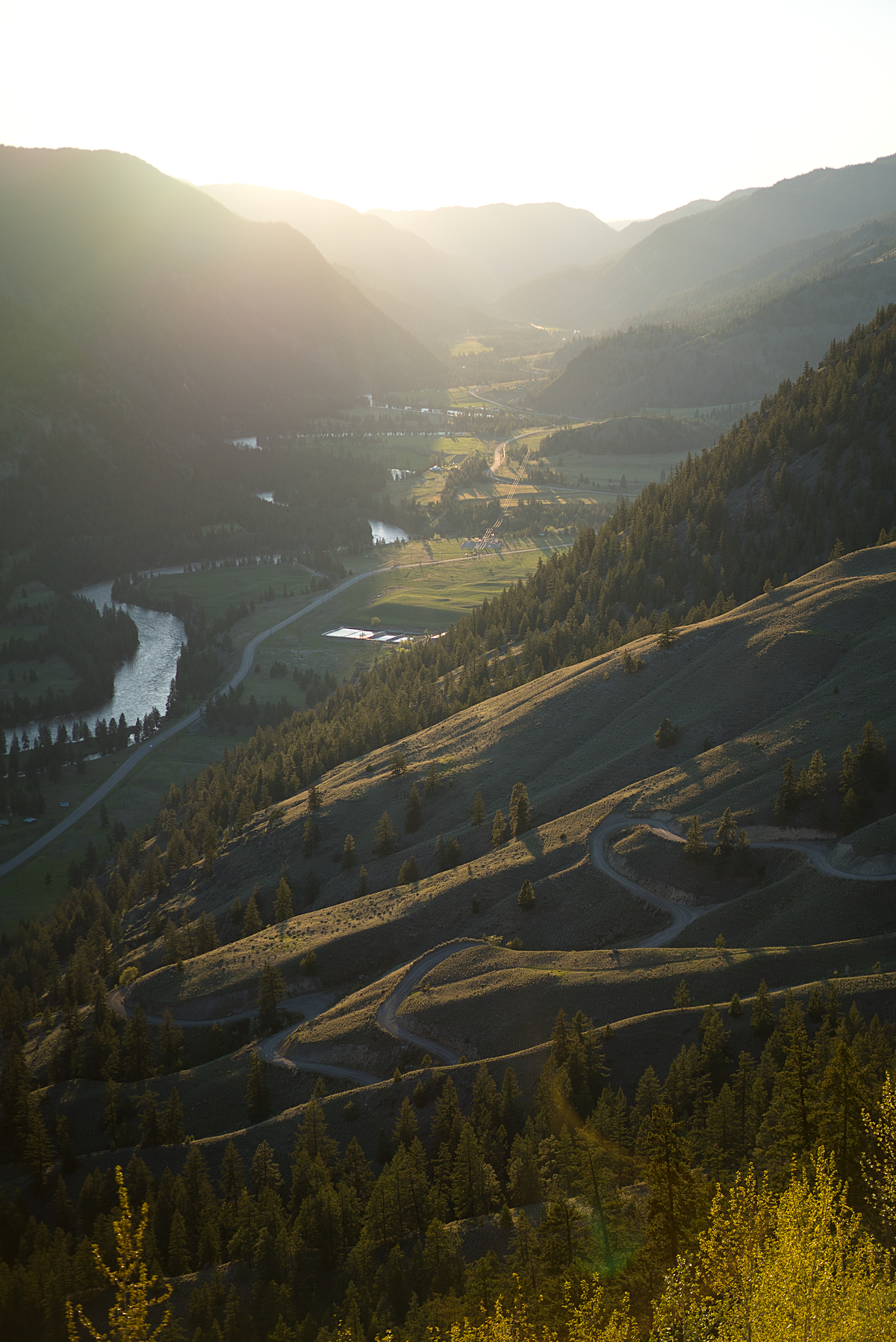 Sunset over the river in Similkameen Valley. The steep mountains lead down to the lush landscape and river below.