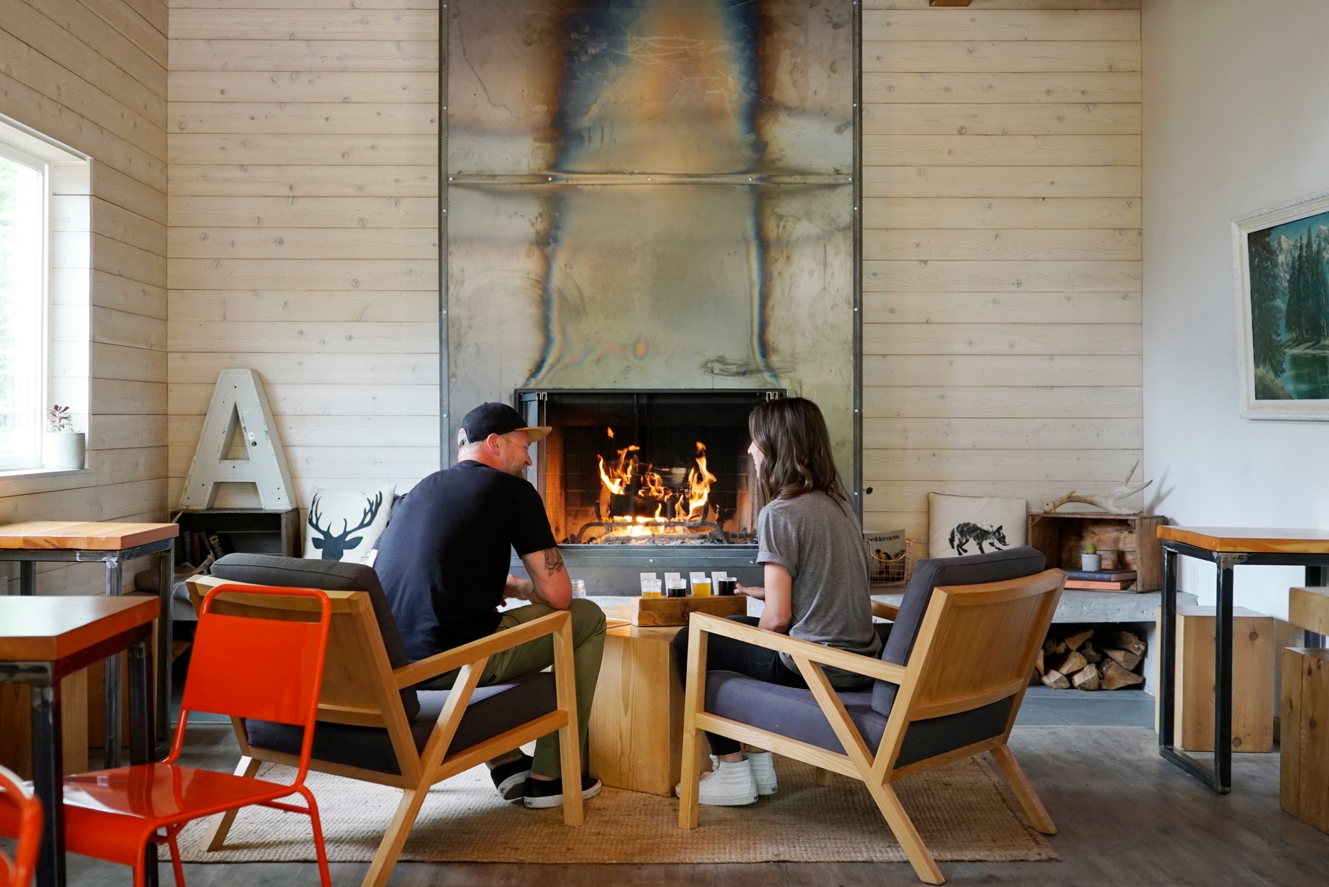 Two people enjoying craft beer in front of the fire at Field House Brewing | BC Ale Trail