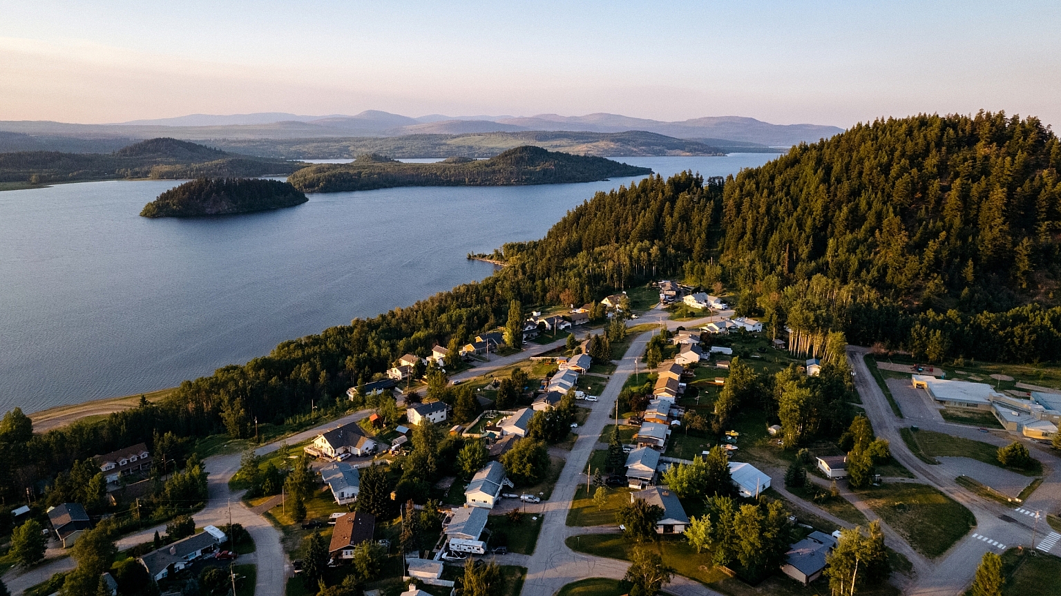 Aerial view of Mouse Mountain and Fraser Lake. Homes dot the residential streets. There is a tree covered hill behind then town.