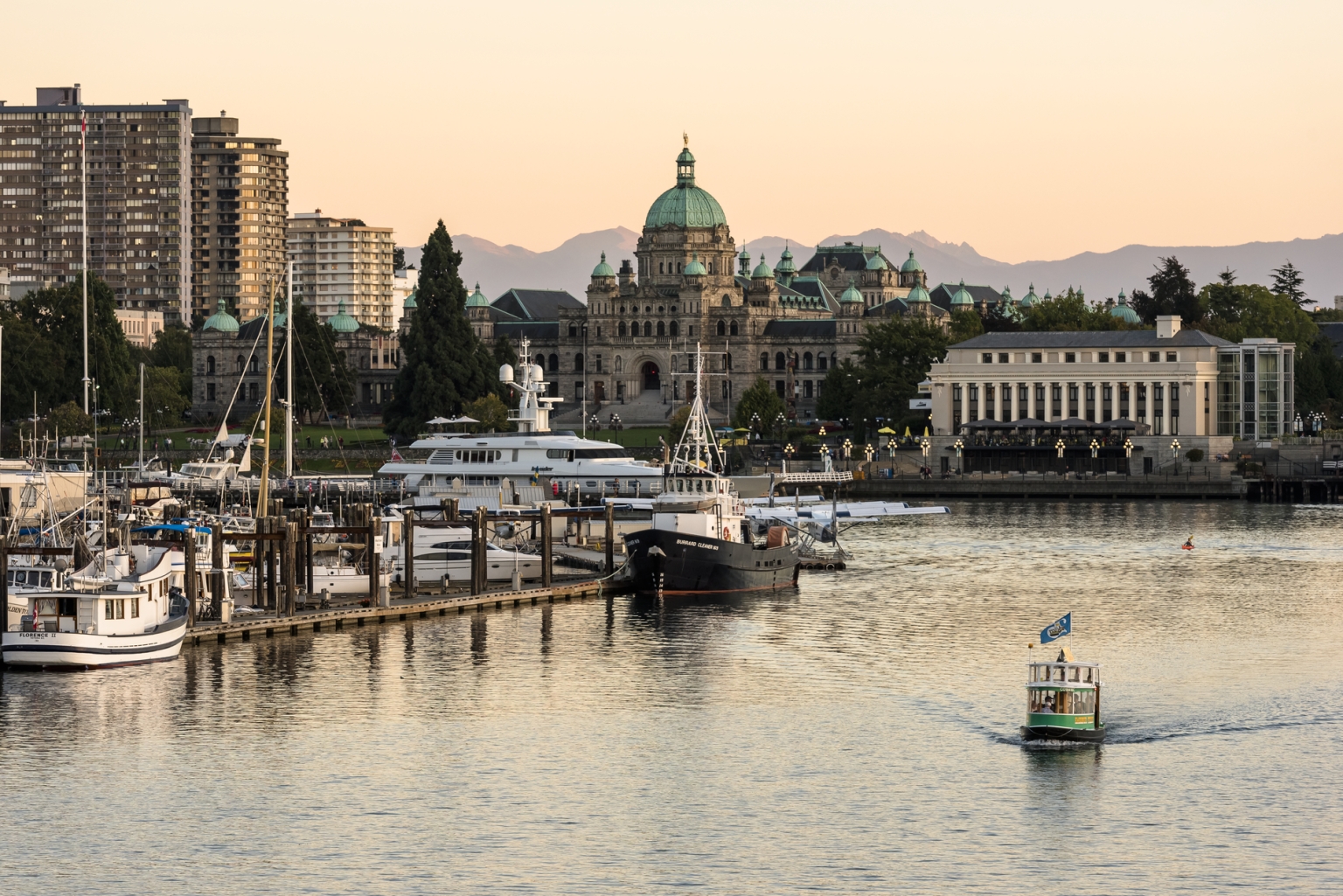 Victoria's Inner Harbour as a boat taxi cruises along the water and the sunsets