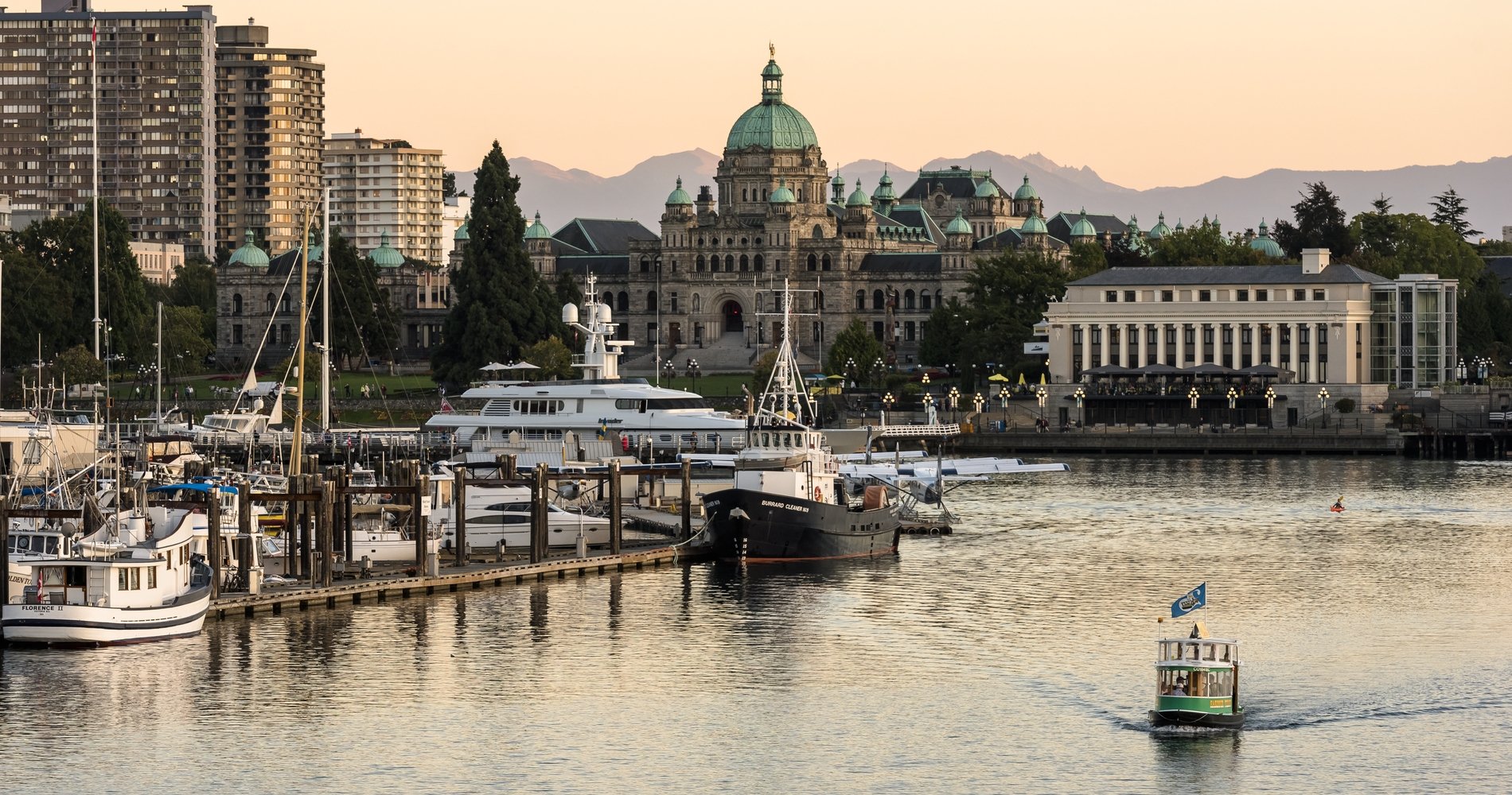 Victoria's Inner Harbour as a boat taxi cruises along the water and the sunsets