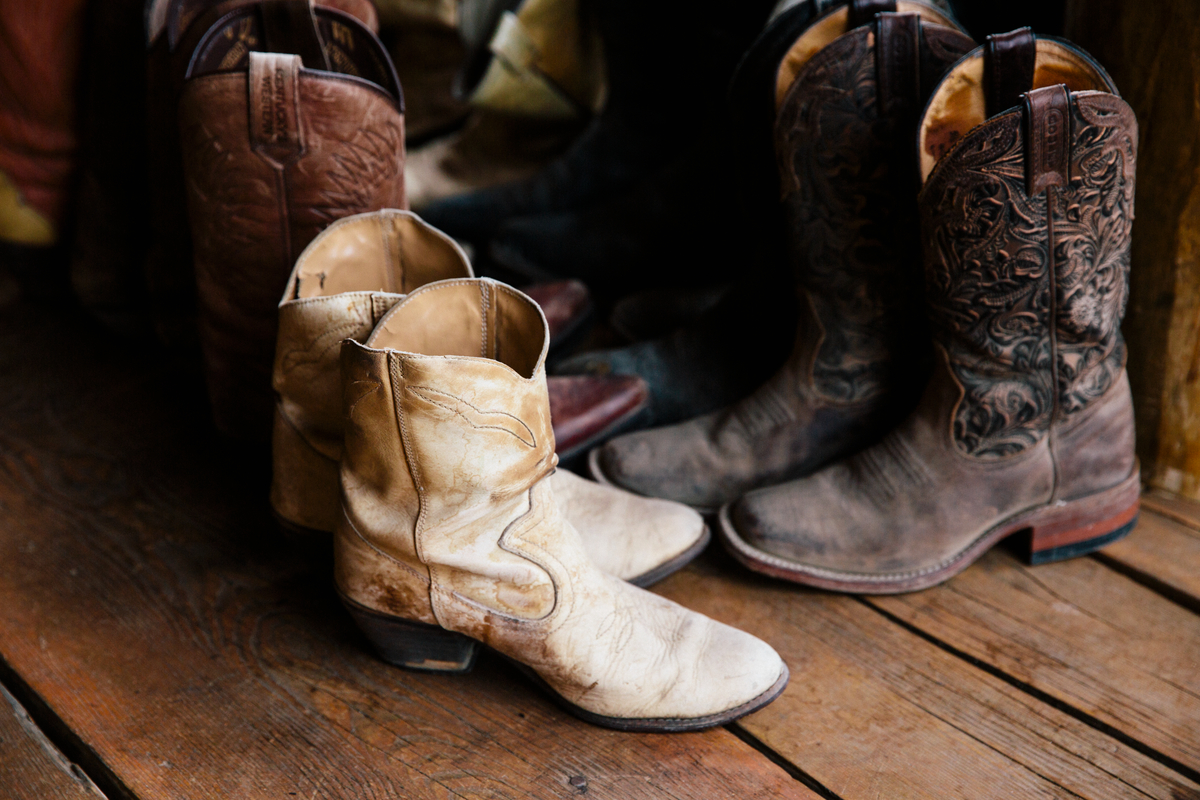 Four pairs of cowboy boots are lined up along a wooden floor at the Terra Nostra Guest Ranch.