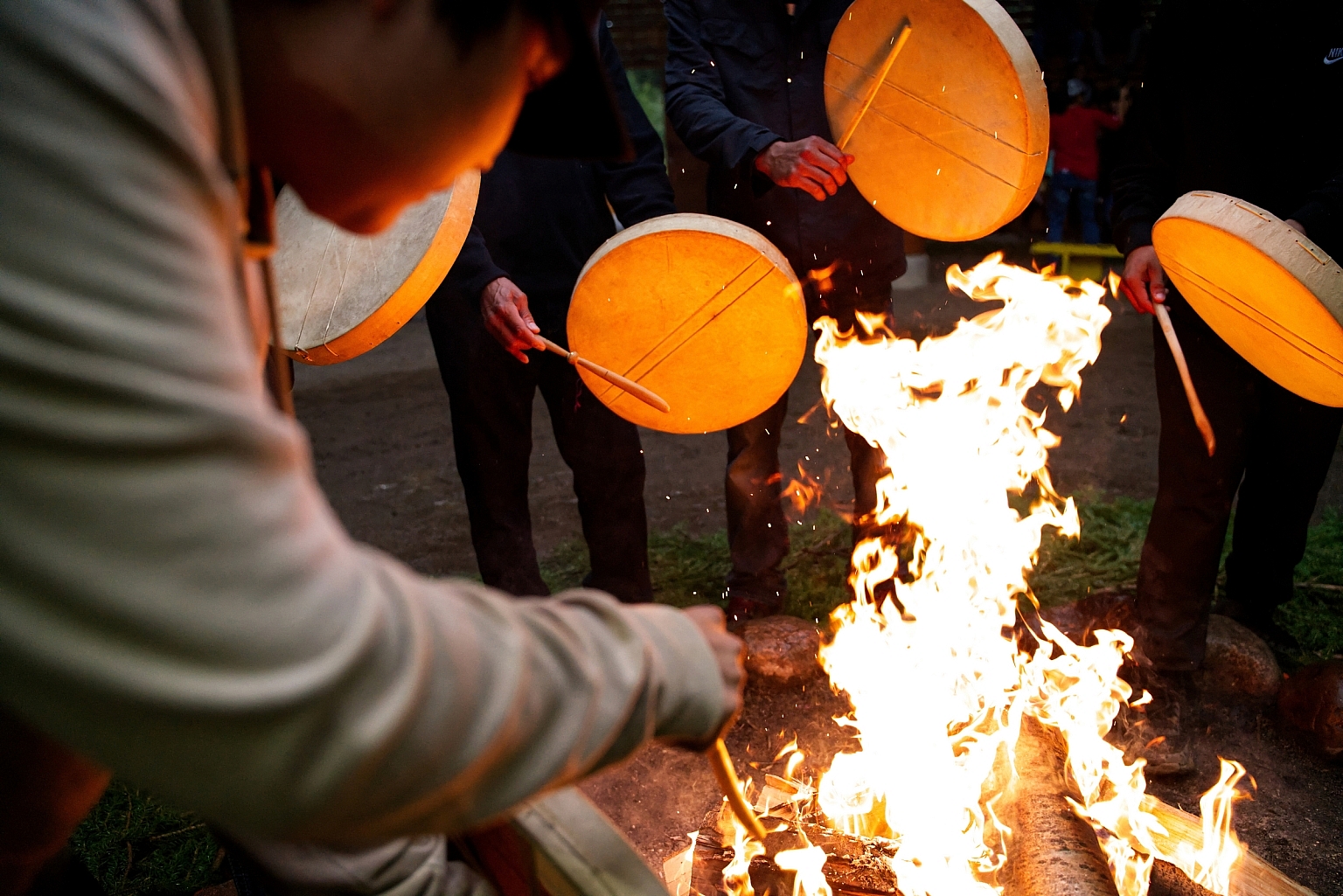 Indigenous People drumming around a fire at the Traditional Dene Drum Dance during Annual Celebration.