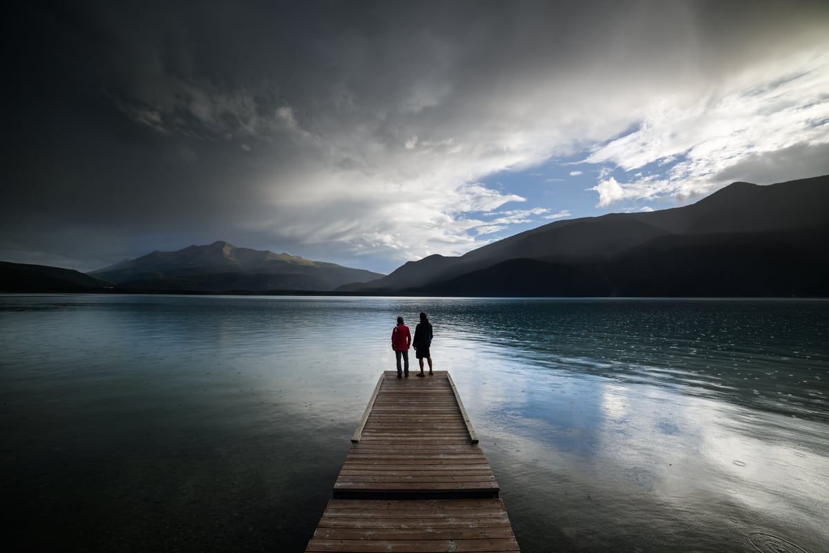 A couple on a pier looking out over Muncho Lake along the Alaska Highway