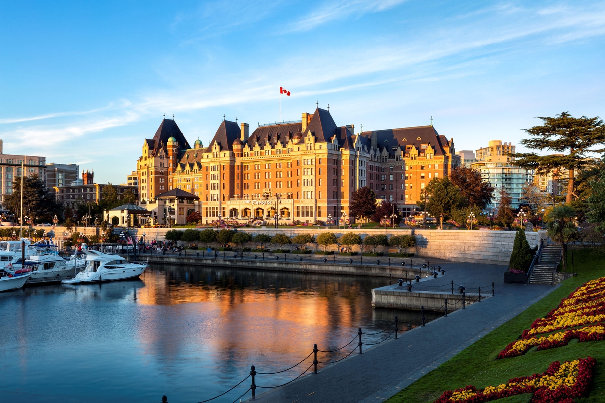 The Fairmont Empress Hotel sits lit up by sunshine. The hotel is directly in front of the harbour.