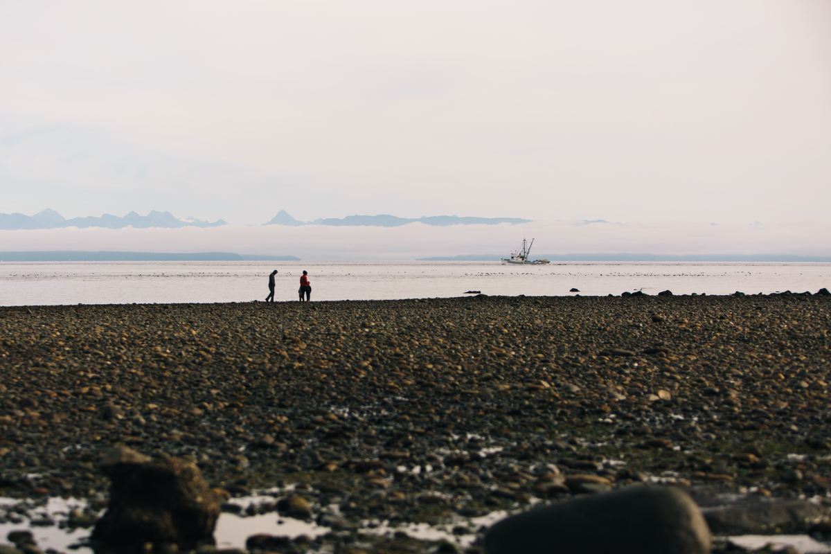 Two people walk along the beach in the distance