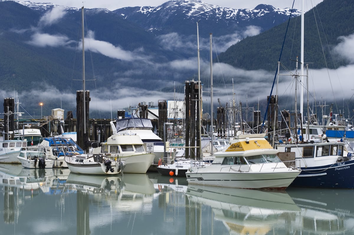 Boats in the harbour on a sunny day at the Bella Coola Marina, mountains behind with a touch of snow at the peaks