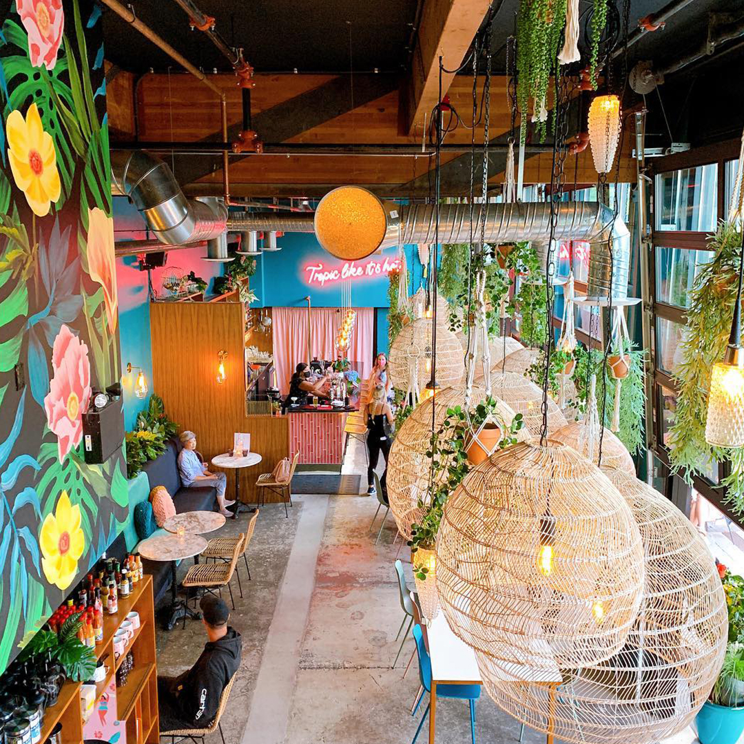 Interior shot of tropical-themed El Segundo restaurant with hanging lights and colourful walls painted with flowers