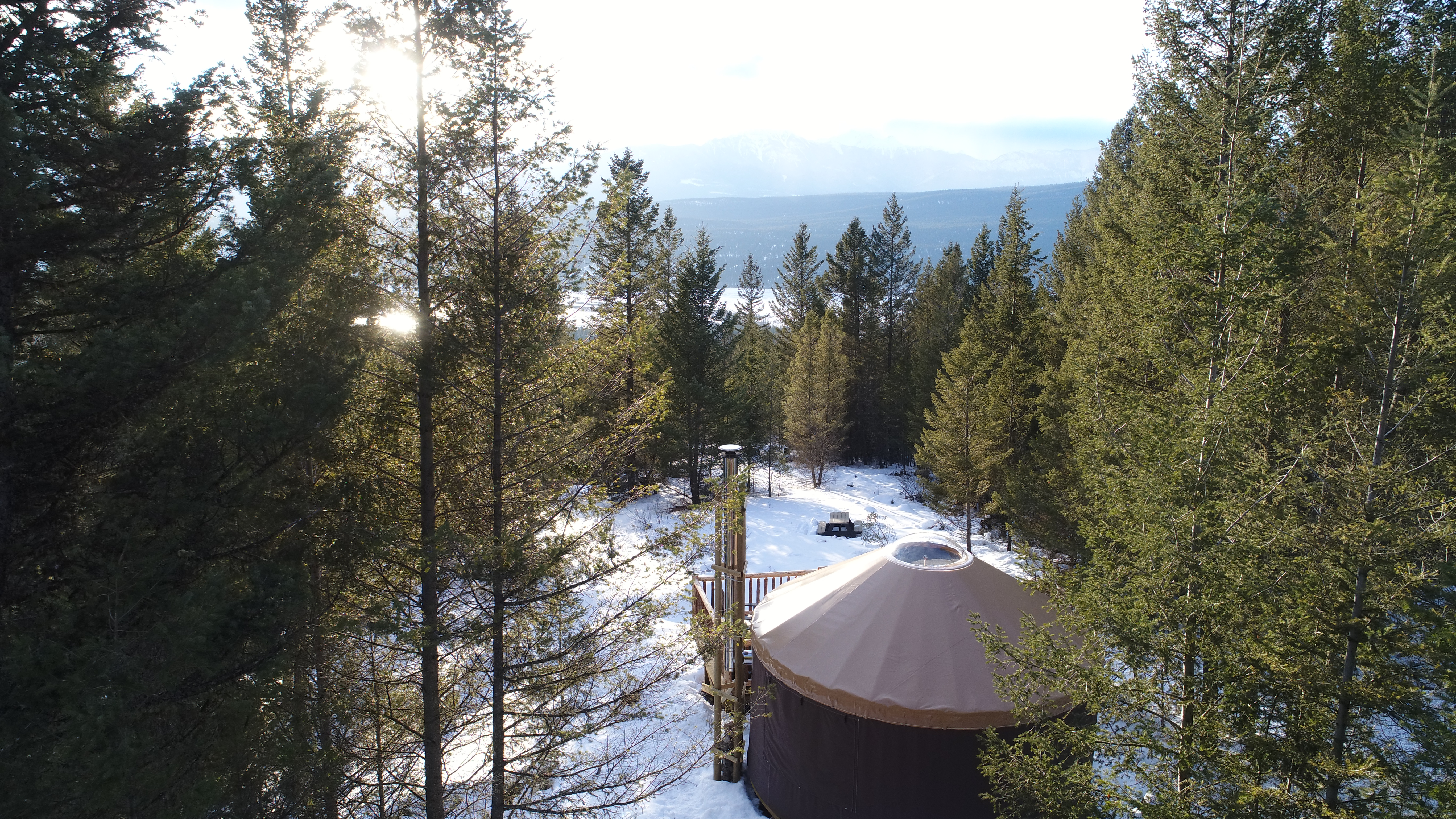 A Yurt surrounded by evergreen trees in the Kootenay Rockies. Snow covers the ground.