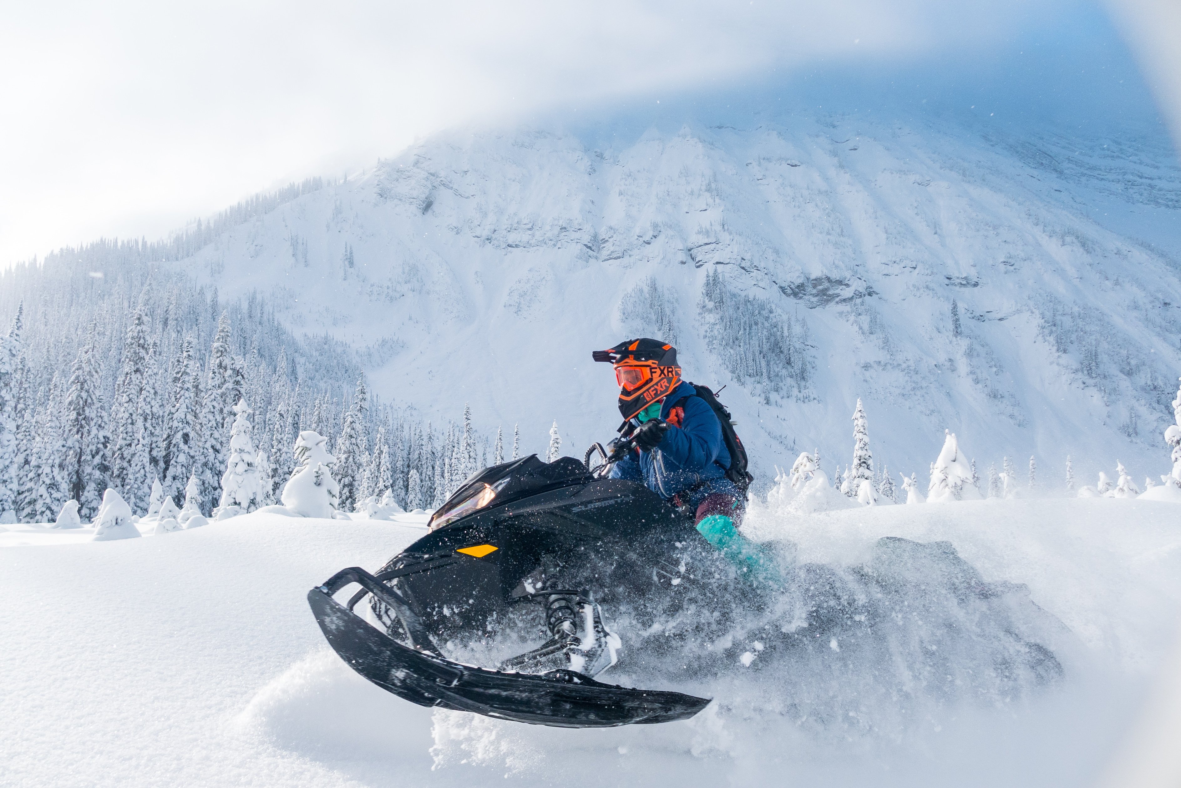 A person rides a snowmobile through the deep snow in the mountains