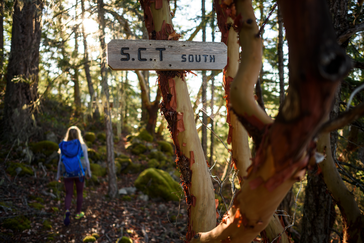 A women hikes along a trail, the sign, 