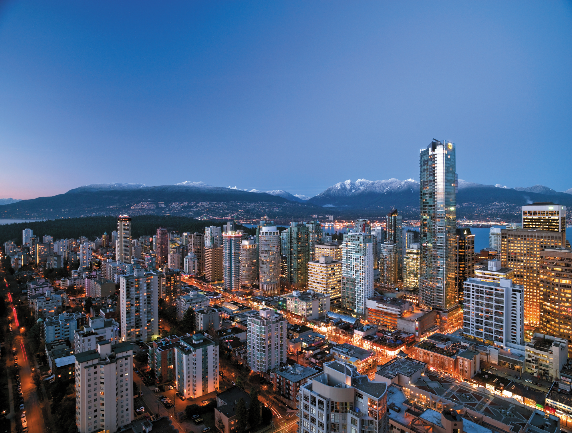 Evening view of skyline of Vancouver with snow on mountains.