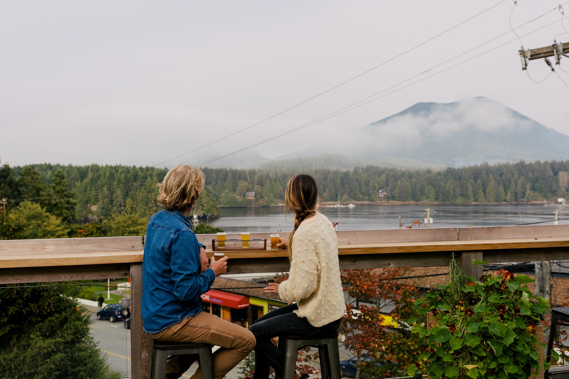 Two people sit on a patio looking out at the ocean and mountains