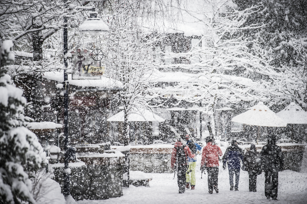 a snowy whistler village with people walking on the pedestrian streets