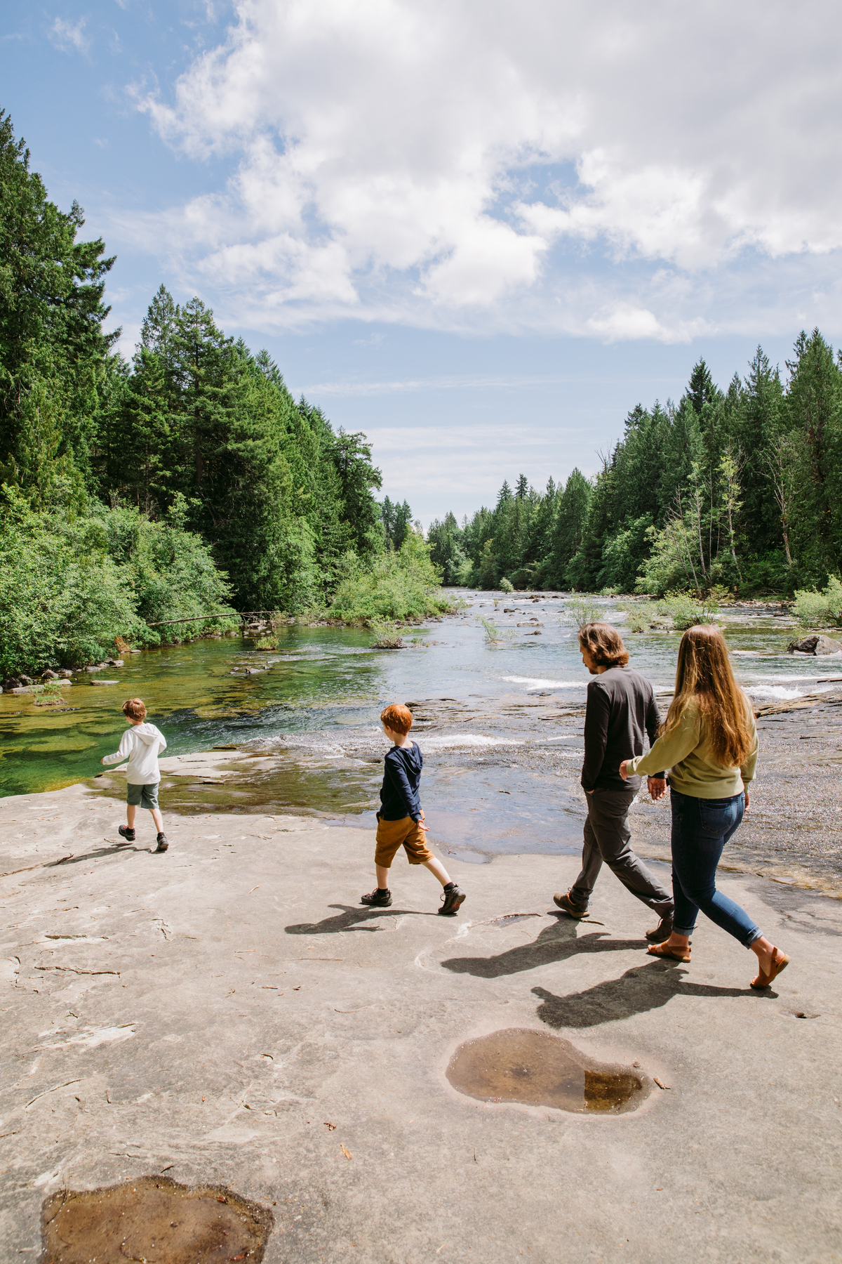 A family walks along the rocky trail beside the water at Nymph Falls