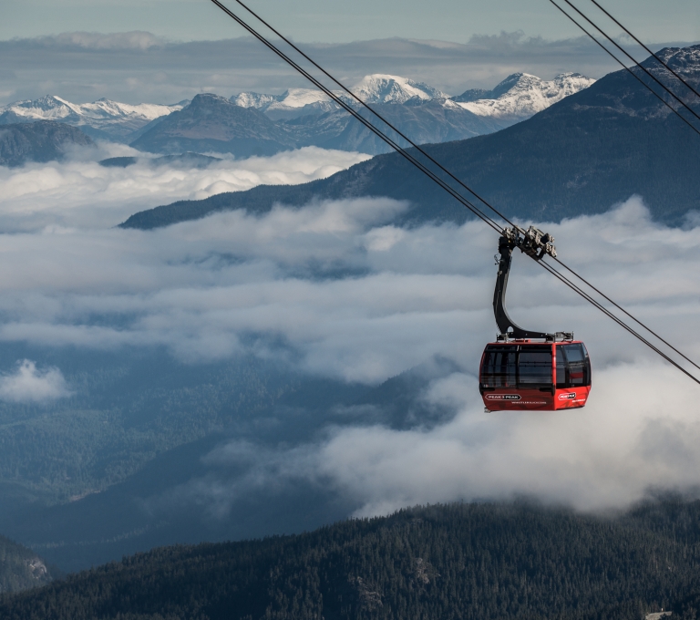 The red Peak to Peak Gondola in Whistler rising above the clouds on the gondola line.