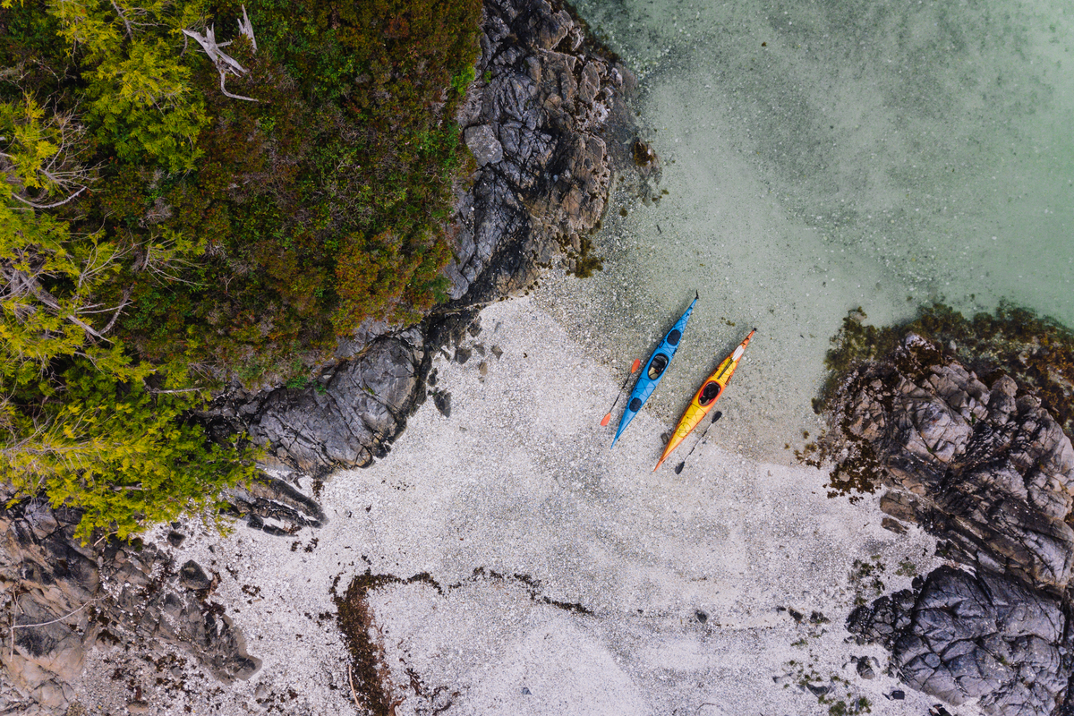 A bird-eye view of two kayaks on a beach, one blue, one yellow, in the Broken Islands Group.