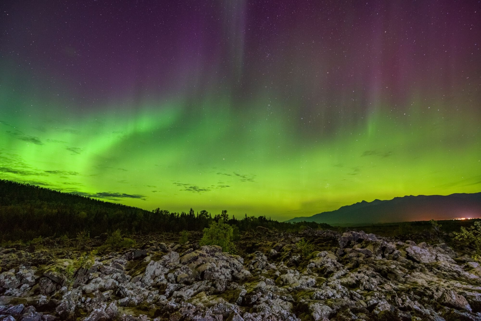 The green and purple Northern Lights illuminate the sky in Nisga'a Memorial Lava Bed Provincial Park.