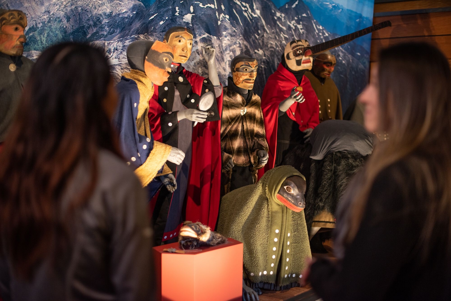 People at the Nisga'a Museum in Laxgalts'ap stand in front of an Indigenous exhibit of traditional clothing.