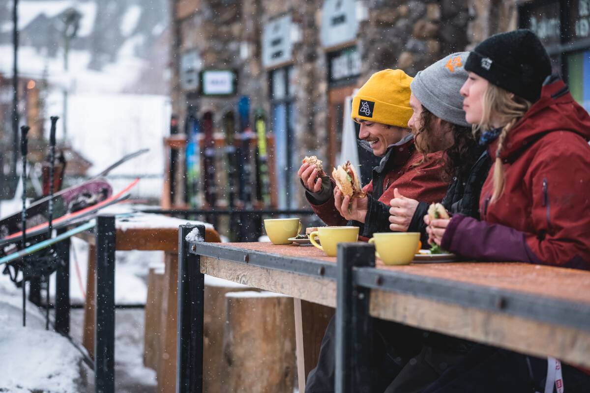 A trio of skiers enjoying lunch and coffee at Kicking Horse Mountain Resort | Reuben Krabbe