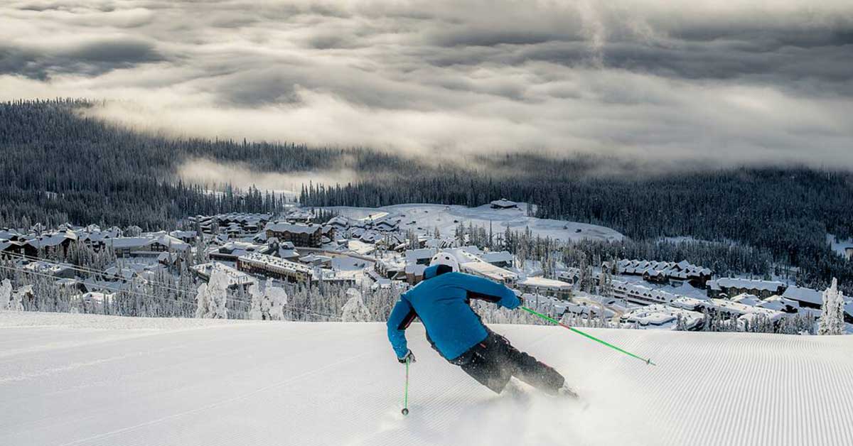 Downhill skier heads down to a colourful village at Big White Ski Resort.