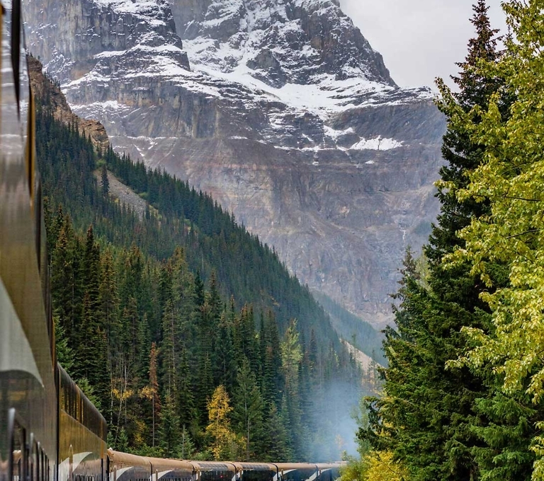 Rocky Mountaineer luxury train rounding a corner through the mountain pass.