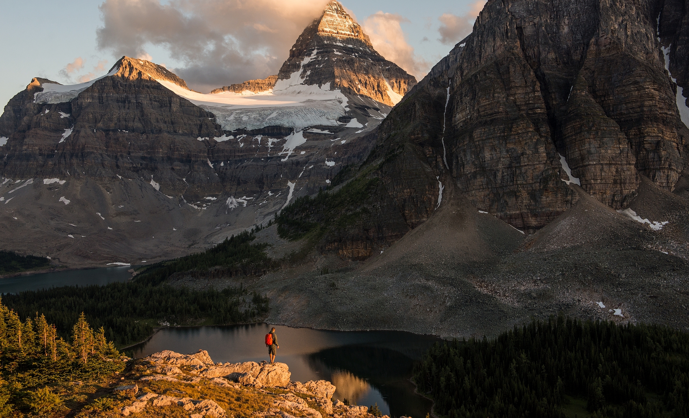 A hiker on the trail to Nublet and Nub Peak, with views of Lake Magog, Sunburst Lake and Mt Assiniboine