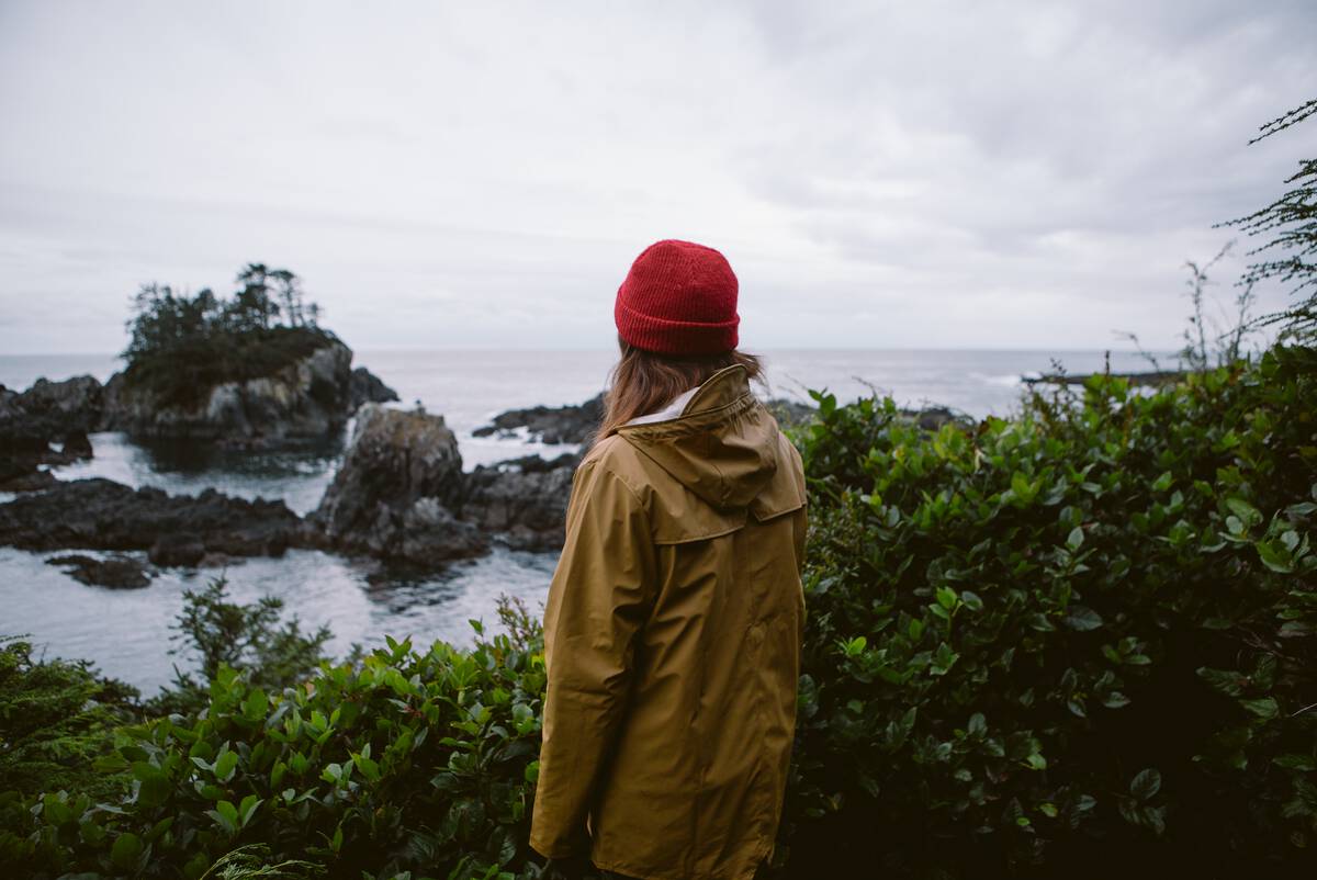 Woman looks at the rocky shoreline from a viewpoint along the Wild Pacific Trail.