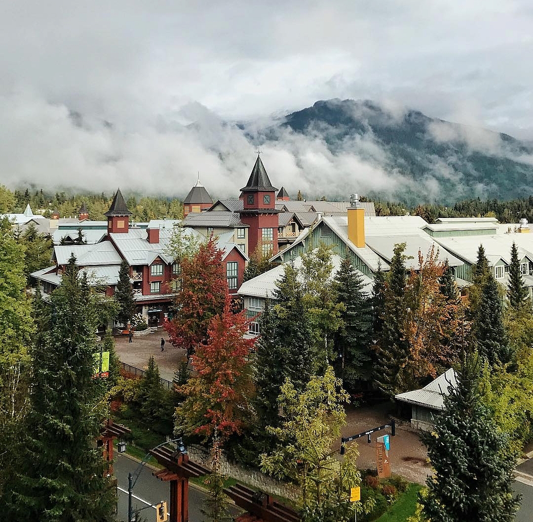 Fall colours in Whistler Village with low clouds and mountains in the background.